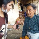 Sarita fits a mini ALD to a woman at Teku Ear Camp